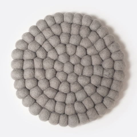 Round felt coaster which is made from little felt balls. The color is light grey.