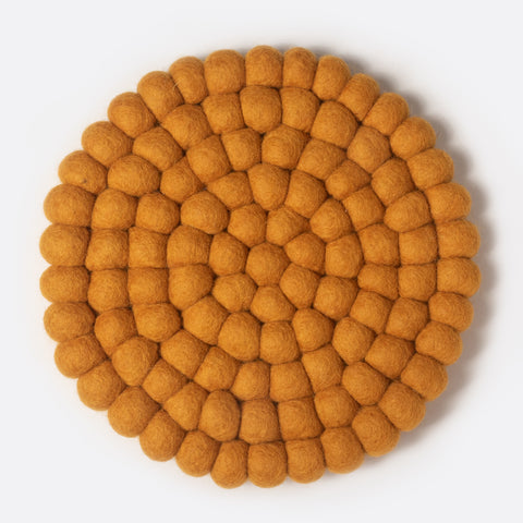 Round felt coaster which is made from little felt balls. The color is yellow mustard.