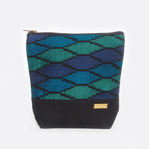 Front view of the Battiayo ,Deep Blue Sea' Sahili bag with handwoven traditional dhaka fabric from Nepal and canvas. The handwoven fabric of the bag has three different shades of blue and a bit of black. The dhaka fabric has a geometric pattern and is handwoven by amazing women. The upper part of the bag is made from the handwoven dhaka. The bottom part of the bag is made from black canvas. The Battiayo label is stitched on the right side on the canvas fabric. The label is made from brass.