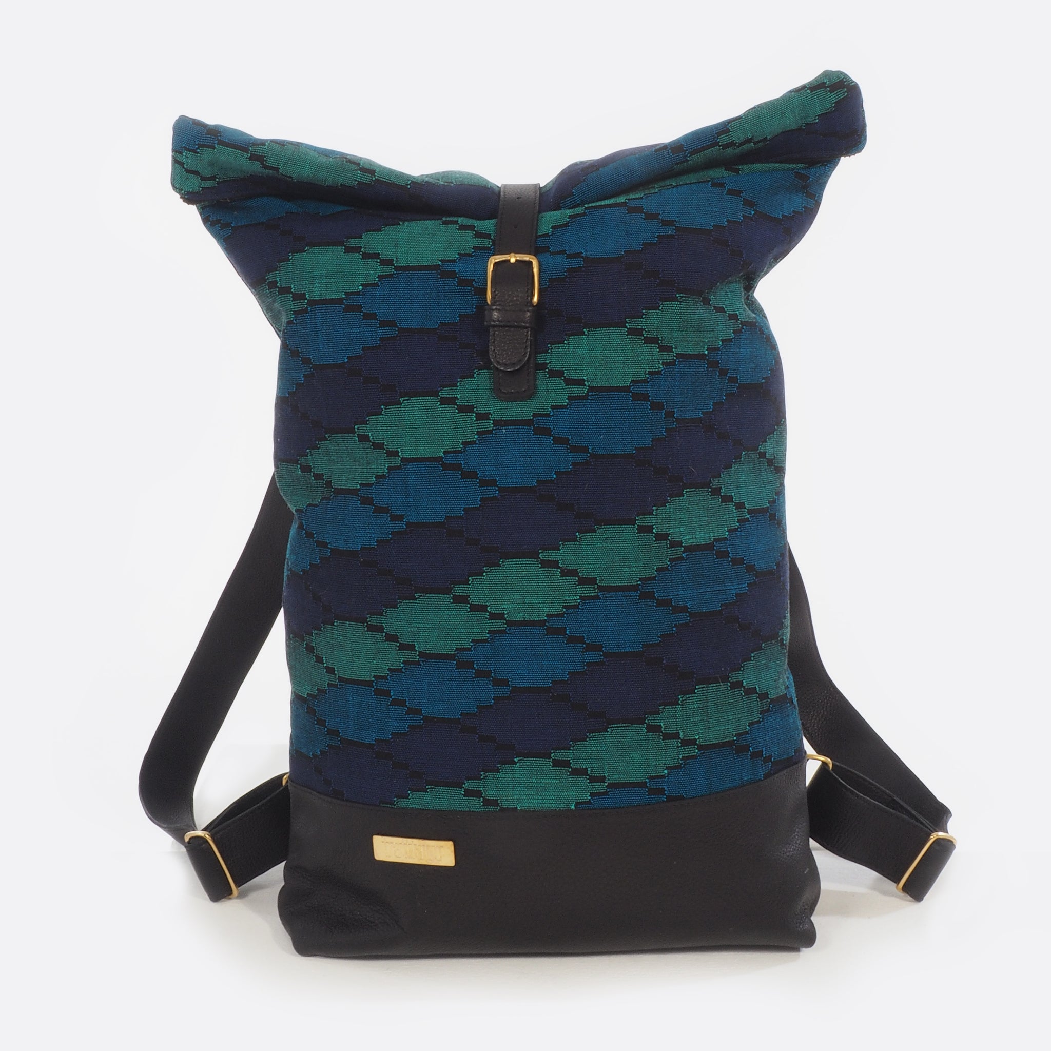 Front view of Battiayo ,Deep Blue Sea' backpack with handwoven traditional dhaka fabric from Nepal and leather. The handwoven fabric of the backpack has three different shades of blue and a bit of black. The dhaka fabric has a geometric pattern and is handwoven by amazing women. The leather is black. The straps and bottom are made from leather. The brass buckles and brass label are also made in Nepal.