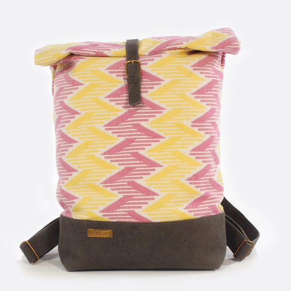Front view of backpack with handwoven traditional dhaka fabric from Nepal and leather.  The fabric  of the backpack is mainly yellow and pink and the leather is grey . The bag has brass buckles