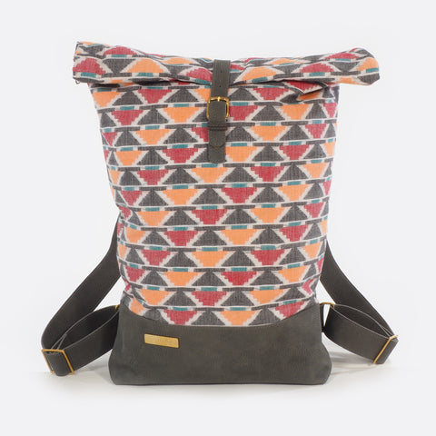 Front view of backpack with handwoven traditional dhaka fabric from Nepal and leather.  The fabric  of the backpack is mainly red, orange , green, white and black and the leather is grey . The bag has brass buckles