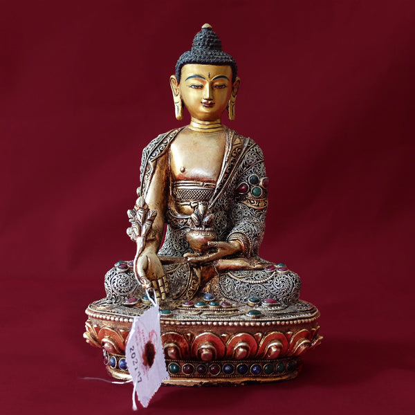 Bhaisajyaguru Statue made of copper, lost wax casting, silver and gold plated, set with filigree and set synthetic gemstones in ruby red, emerald green, lapis lazuli blue. The face is set in gold. Handmade in Nepal