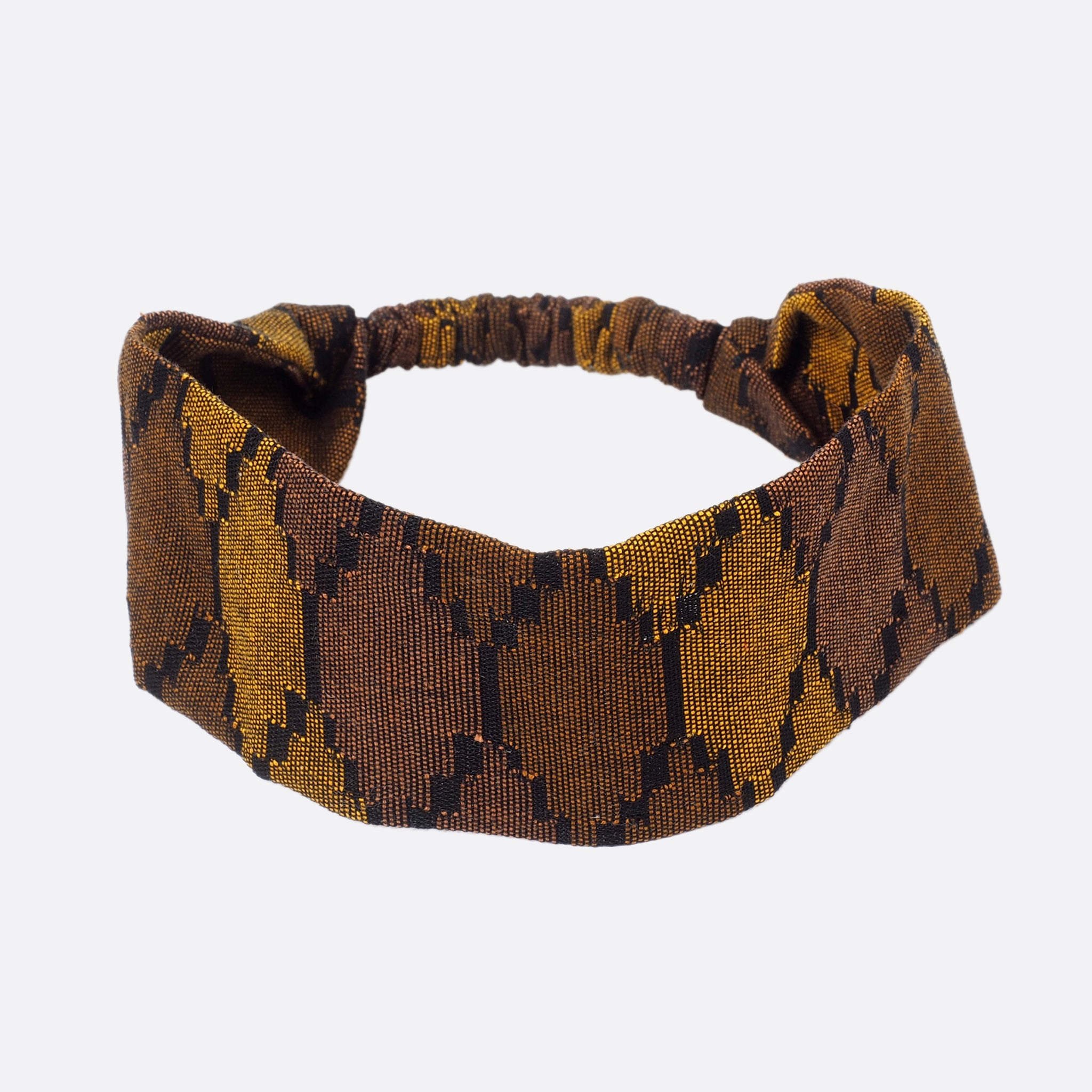Top view of the Battiayo Deep Brown Earth headband. The handwoven traditional dhaka fabric has three different shades of brown and a bit black. The dhaka fabric has a geometric pattern and is handwoven by amazing women. The pattern looks like honeycombs. 