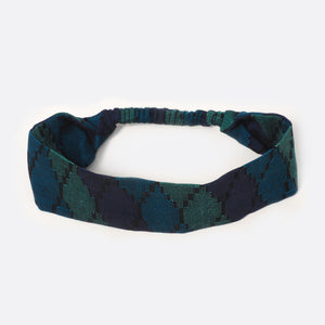 Top view of the Battiayo Deep Blue Sea headband. The handwoven traditional dhaka fabric has three different shades of blue and a bit black. The dhaka fabric has a geometric pattern and is handwoven by amazing women. The pattern looks like honeycombs. 