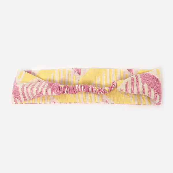 Back view of the Pink& Yellow Battiayo headband. The small scrunchy part, which gives the headband the elasticity is shown. The elastic part is covered with the dhaka fabric