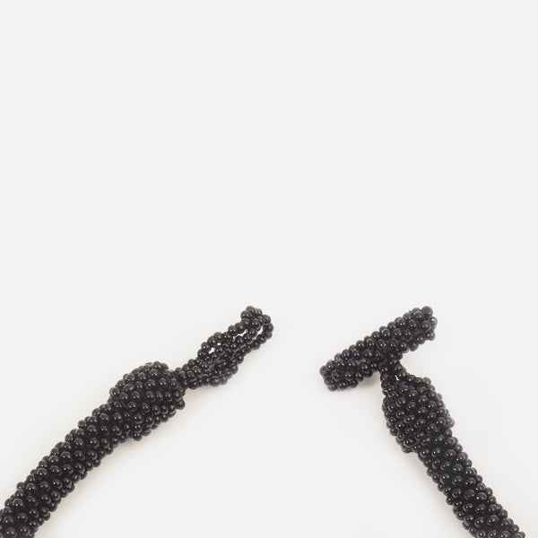 Close up of the necklace clasp. The clasp is open. The small glass beads are shown. 