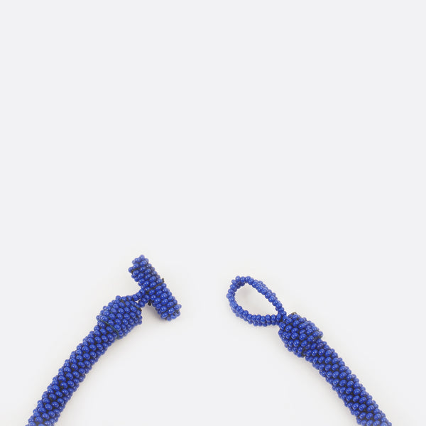Close up of the necklace clasp. The clasp is open. The small glass beads are shown.