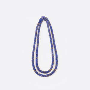 Front view of the Battiayo beaded necklace. It is a double-string necklace. One string is a bit longer than the other string. The necklace is mainly blue and has small golden dots