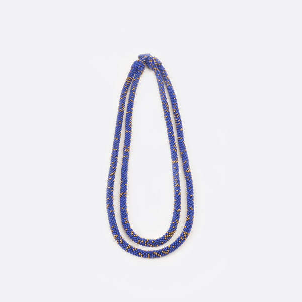 Front view of the Battiayo beaded necklace. It is a double-string necklace. One string is a bit longer than the other string. The necklace is mainly blue and has small golden dots