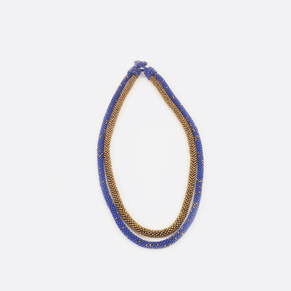 The golden string of the necklace is a bit shorter as the blue with golden dots string.
