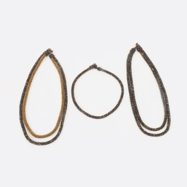 The handmade Battiayo necklace in black with golden dots is existing in three variations. All three variations are shown on the picture. On the left is the double-string necklace with both strings in black with golden dots. In the middle is the single-string necklace, which is much shorter than the double-string necklace. On the right is the double-string necklace with the longer string in black with golden dots and the shorter string completely golden.