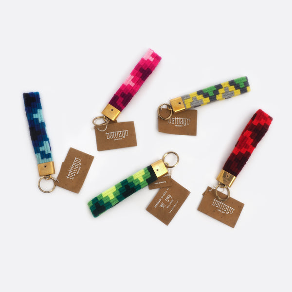 5 differently colored key chains: one has different shades of pink, one has different shades of blue, one has different shades of red, ones has different shades of green and one is grey, yellow and green