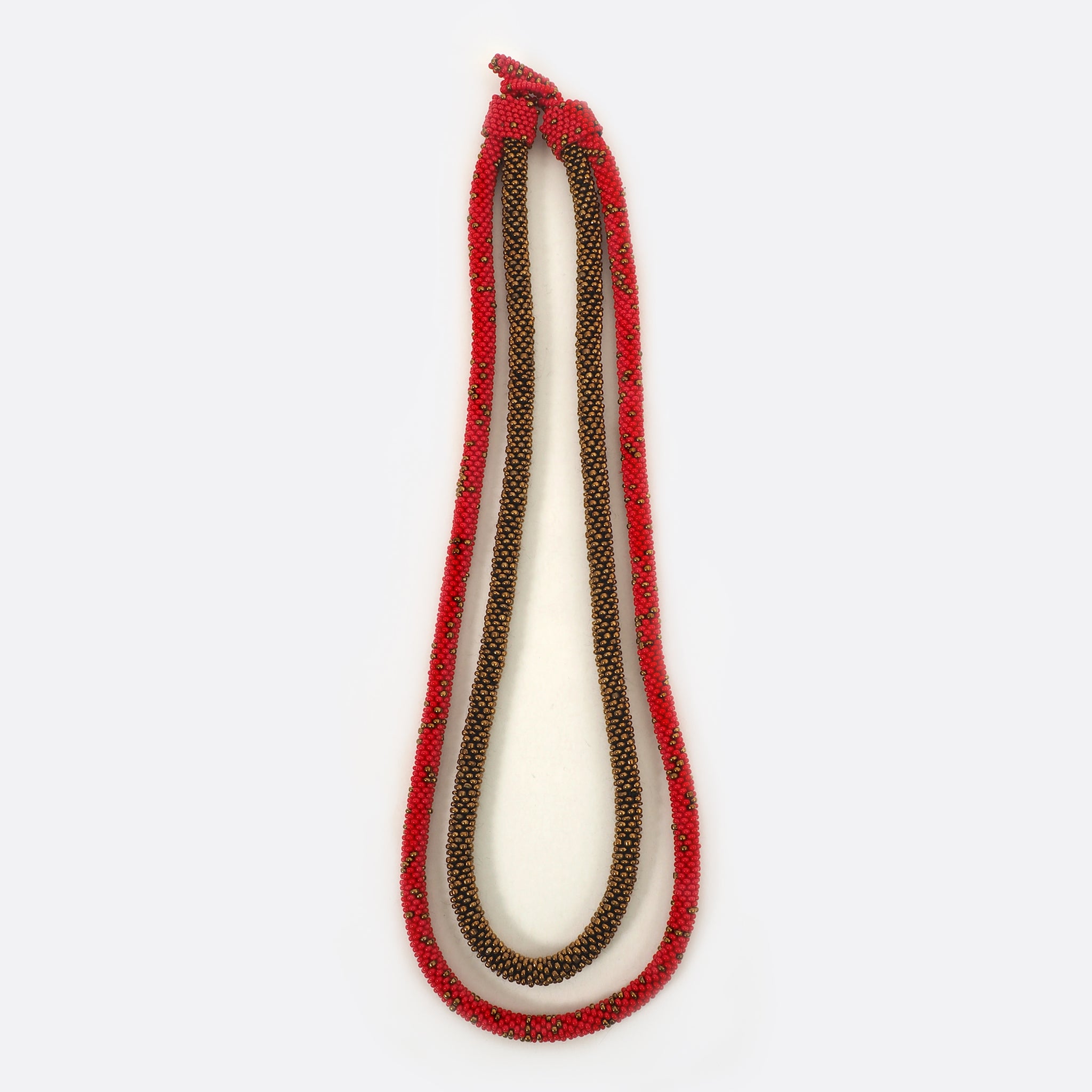 Front view of the Battiayo beaded necklace. It is a double-string necklace. One string is a bit longer than the other string. One string is red and has small golden dots. The glass beads of the other string are all golden. 