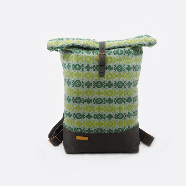 -Front view of Battiayo ,Cross Light Green' backpack with handwoven traditional dhaka fabric from Nepal and leather. The handwoven fabric of the backpack has different shades of green and a bit of white. The dhaka fabric has a geometric pattern and is handwoven by amazing women. The leather is grey. The straps and bottom are made from leather. The brass buckles and brass label are also made in Nepal. 