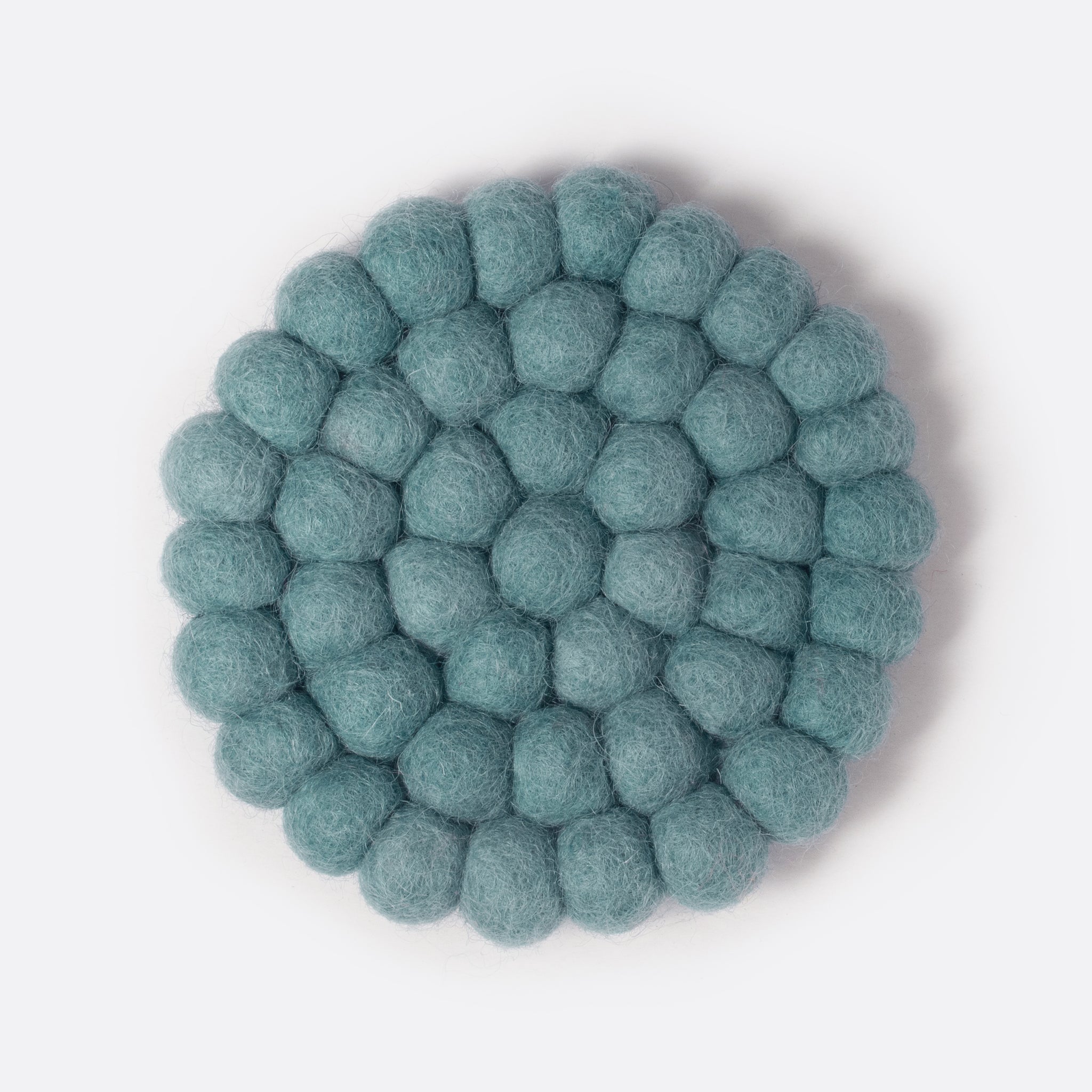 Round felt coaster which is made from little felt balls. The color is light blue-grey.