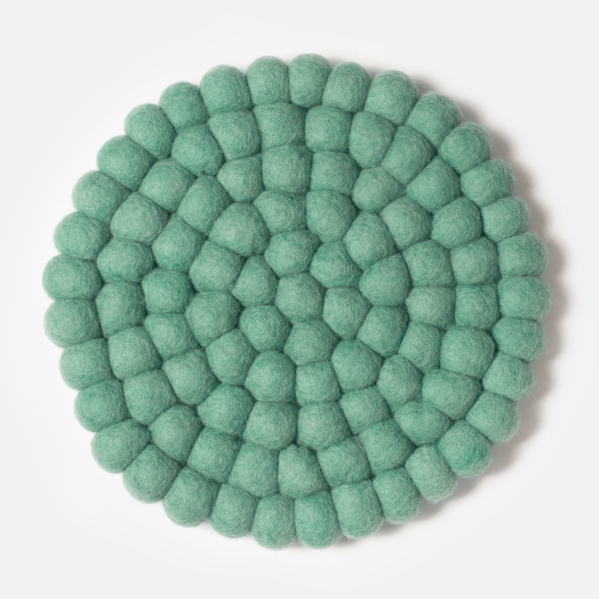 Round felt coaster which is made from little felt balls. The color is pale green.