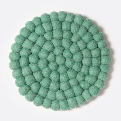 Round felt coaster which is made from little felt balls. The color is pale green.