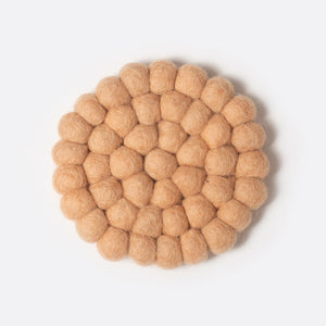 Round small felt coaster which is made from little felt balls. The color is salmon.