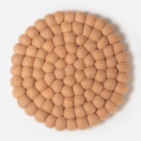 Round felt coaster which is made from little felt balls. The color is salmon.