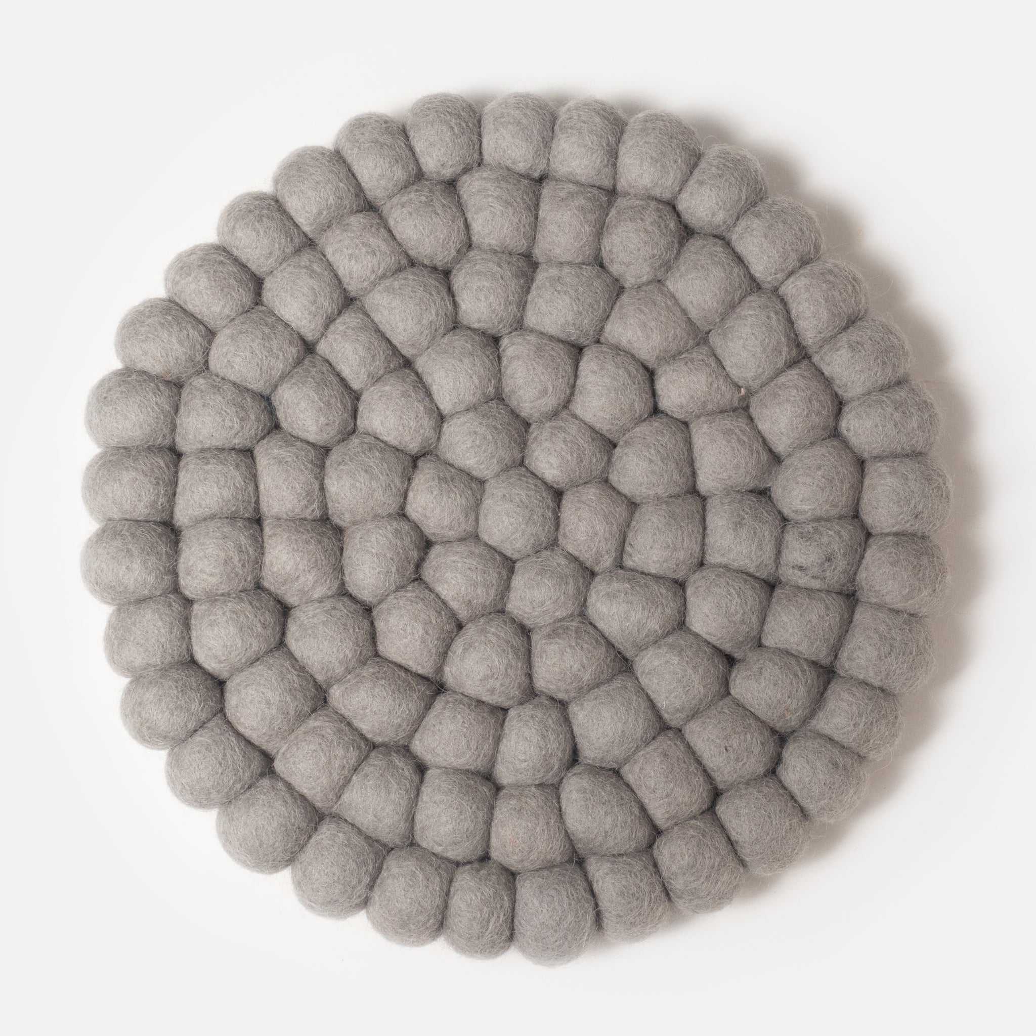 Round felt coaster which is made from little felt balls. The color is light grey.