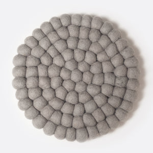Round felt coaster which is made from little felt balls. The color is light grey.