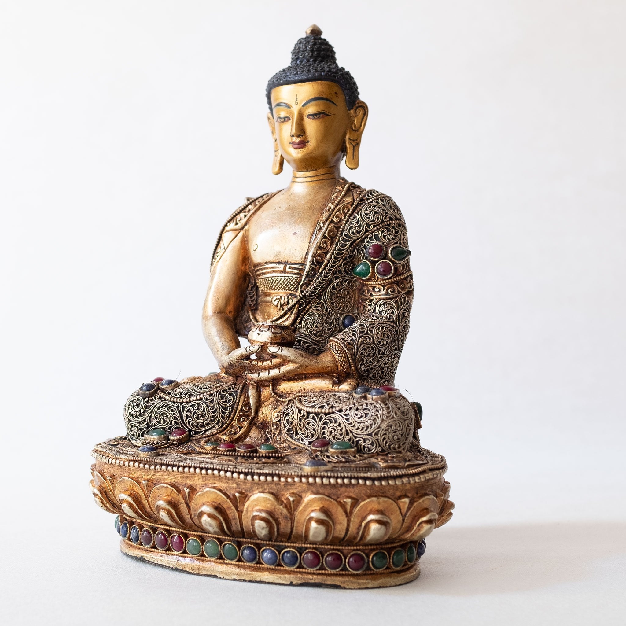 Amitabha Buddha Statue made of copper, lost wax casting, silver and gold plated, set with filigree and set synthetic gemstones in ruby red, emerald green, lapis lazuli blue. The face is set in gold. Handmade in Nepal
