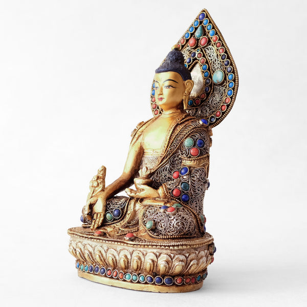 Bhaisajyaguru statue, body from copper, lost wax casting, decorated with fine filigree, gold and silver plated, set with turquoise, coral and lapis lazuli. The face is set in gold. Handmade in Nepal