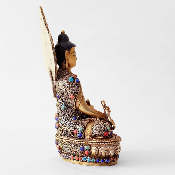 Bhaisajyaguru statue, body from copper, lost wax casting, decorated with fine filigree, gold and silver plated, set with turquoise, coral and lapis lazuli. The face is set in gold. Handmade in Nepal
